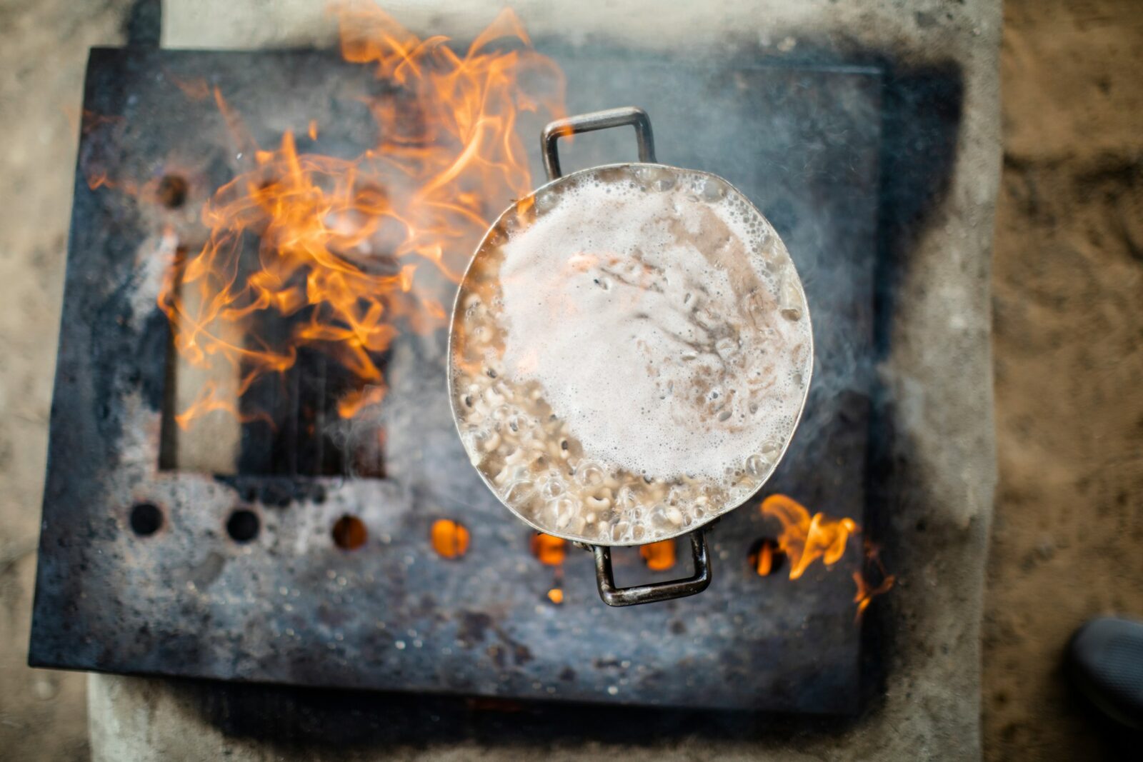Water at a gentle simmer in a pot on a stovetop — the start of the boiled rice-water method.